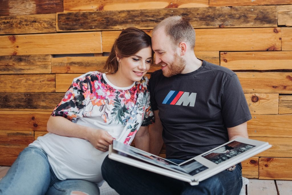 Pregnant couple looking at their wedding album together.